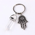 Macro shot of crystal hexagonal prism and Hamsa hand pendant on a silver keychain - Clear