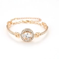 Dettaglio di un bracciale dorato con grande zircone tondo e piccoli cristalli - Oro