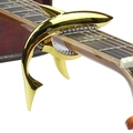 Golden shark-shaped metal guitar capo with white padding on a wooden guitar neck - Blister Packaging / Luxury Gold