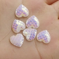 Macro view of heart-shaped iridescent fish scale resin charms held in hand - 12mm Pearl White Iridescent
