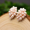 Handmade cluster pearl stud earrings with rose gold wire wrap on a natural wood surface - White