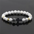 Dettaglio del bracciale con perline in turchese bianco, croce nera e accenti dorati - Howlite