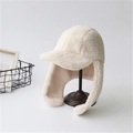 Winter-Lammfell-Fliegermütze in Beige mit Ohrenklappen auf einem hölzernen Hutständer - Einheitsgröße / Milchweiß