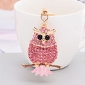 Portachiavi a forma di gufo con strass rosa e lega dorata appeso a una tazza bianca - Civetta in Piedi / Rosa