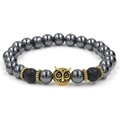 Detailed close-up of golden owl charm and black lava beads on a stone bracelet - Owl / Antique Gold