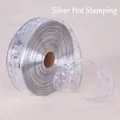 Détail du ruban argenté estampé à chaud avec étoiles et notes sur résille transparente - Monocouche Doré Argent