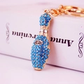Golden bowling pin keychain with blue sparkling crystals and elegant book background - Blue
