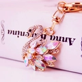 Golden swan keychain with sparkling crystals and rainbow gemstones on a book background - Colorful