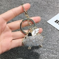 Golden flying pig keychain with sparkling crystals and wings held in hand - Basic Style / White