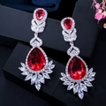 Detailed macro of red pear-cut drop earrings with AAA cubic zirconia on display stand - Red