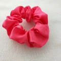 Close-up of vibrant red satin scrunchie with silky texture on soft plush background - Brilliant Red