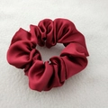 Close-up of a premium red satin silk scrunchie on soft white plush fabric background - True Red