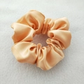 Detail of a smooth apricot satin scrunchie showing glossy silk texture and durable elastic - Apricot