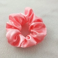 Detail of pink satin silk scrunchie with smooth texture and glossy finish on soft white fabric - Light Pink