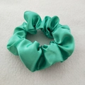 Macro detail of glossy green satin scrunchie showing smooth texture and soft folds - Turquoise Green