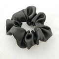 Close-up of a premium black satin scrunchie with a soft glossy texture and high elasticity - Black