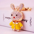 Golden rabbit keychain with sparkling rhinestones and yellow dress on white book - Yellow