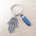Détail de la main de Hamsa argentée et pendentif cristal bleu sur surface bois - Bleu Fantaisie