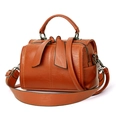 Brown faux leather cylindrical handbag with top handle and shoulder strap on white backdrop - Yellow