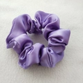 Close-up of smooth purple satin fabric scrunchie with a glossy silk texture finish - Purple