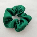 Detailed view of the glossy green satin silk scrunchie on a white textured background - Emerald Green