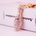 Sparkling gold bowling pin keychain with crystal rhinestones on a decorative book - White