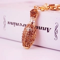 Golden bowling pin keychain with brown crystals shown against a vintage book background - Champagne