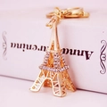 Porte-clés Tour Eiffel doré orné de strass brillants, présenté sur un fond de livre élégant - Blanc