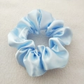 Detailed top view of light blue satin scrunchie on white textured background - Light Blue