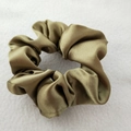 Macro view of silky olive green satin scrunchie showing glossy texture and soft folds - Olive Green