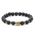 Makroaufnahme von schwarzen Lavasteinperlen und goldenem Buddhakopf auf dem Armband - Buddha-Antikgold