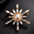Macro shot of snowflake brooch with gold base, center pearl and clear crystals - Sun