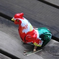 Retro wind-up hopping chicken toy in colorful vintage metal finish on wooden surface - Tin Rooster