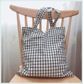 Minimalist black and white checkered canvas tote bag hanging on a wooden chair - White Base Black Grid - Double Straps (Handheld/Shoulder)