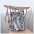 Gros plan détaillé du sac cabas en coton vichy bleu et blanc suspendu à une chaise - Fond Blanc Carreaux Bleus - Bandoulière Unique