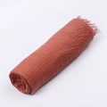 Terracotta voile scarf with crinkle texture and fringe trim rolled for display - Rust red