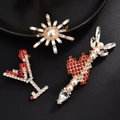 Detailed view of three alloy brooches with rhinestones and pearls on a black background - Cupid's Arrow