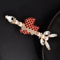 Detail of a golden rocket brooch with red rhinestones and pearls on dark background - Cupid's Arrow
