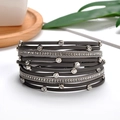 Detailed close-up of layered dark grey leather bracelet with crystal encrusted metal rings - Gray