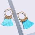 Pendientes dorados de moda con borlas de seda azul brillante sobre fondo geométrico - Azul