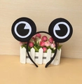 Close-up of black frog eyes headband displayed on white fence for party cosplay - Black Frog