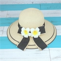 Beige woven straw sun hat with black bow and dual plumeria flowers on wooden background - M (56-58cm) / Beige