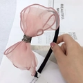 Close-up of pink lace bow headband with black rhinestones held against a magazine - Mesh Pink