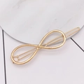 Detail shot of a minimalist gold infinity symbol hair clip on a marble surface - Infinity