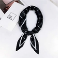 Détail du foulard plissé en soie noir et blanc noué sur un bureau blanc épuré - Style 12 Plissé Pois Noir