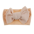 Detailed view of apricot baby nylon headband with a large textured waffle knit bow - Nude with White Bow