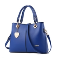 Blaue Handtasche aus PU-Leder mit goldenen Metallteilen und Herzanhänger auf Weiß - Königsblau