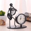 Vintage black iron desk clock featuring a musician figure figurine on a wooden surface - C67 French Horn Clock