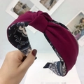 Detail view of burgundy knotted headband featuring a paisley patterned inner fabric lining - Burgundy