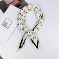 Détail d'un foulard plissé en soie beige à pois noirs et rayures noué avec élégance - Style 15 Plissé Pois Beige